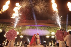 “A mesmerizing wedding moment with the bride and groom sharing a kiss under fireworks and fire effects, surrounded by rose petals and luxurious decor.”