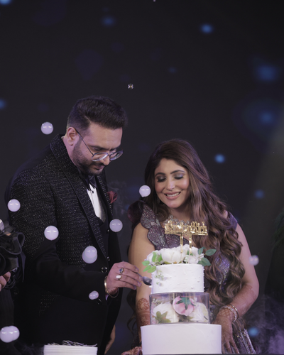 Couple cutting a white floral cake at a glamorous celebration with bubble effects