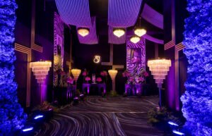 Lavish black and purple zebra-themed party decor with chandeliers and floral arrangements