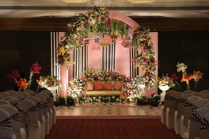 Indoor wedding stage with floral arch and pastel pink theme