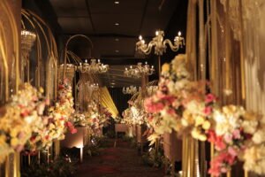 Golden arch floral wedding entry walkway with chandeliers and pastel flower arrangements