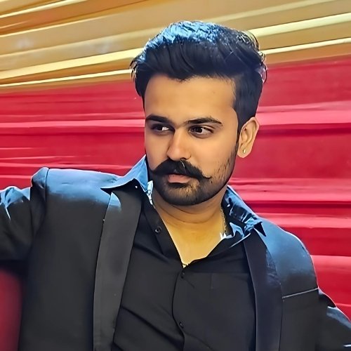 Man with mustache in black suit sitting on red stairs