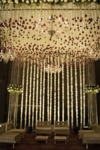 Grand floral wedding stage decor with hanging garlands, chandeliers, and royal seating