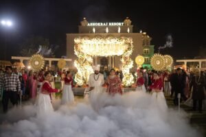 Bride and groom making a grand wedding entrance with smoke effects and dancers at Ashokraj Resort, planned by Milaap Weddings in Indore.