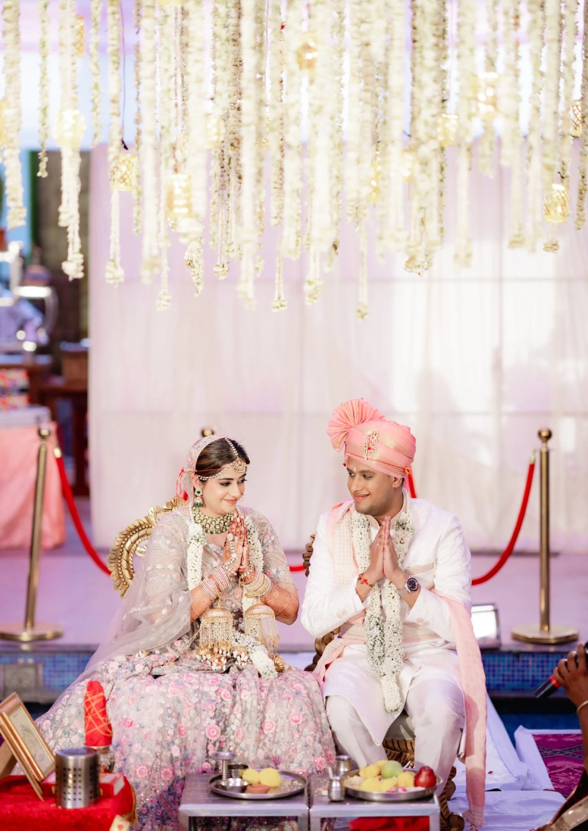 Bride and groom in traditional attire during a wedding ceremony, with floral decorations.