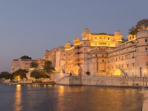 City Palace Udaipur illuminated at dusk by Lake Pichola