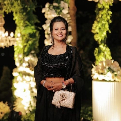 Dr. Khushboo Kothari Makwana, co-founder of Milaap Weddings, posing in elegant black attire at a beautifully decorated wedding venue in Indore.